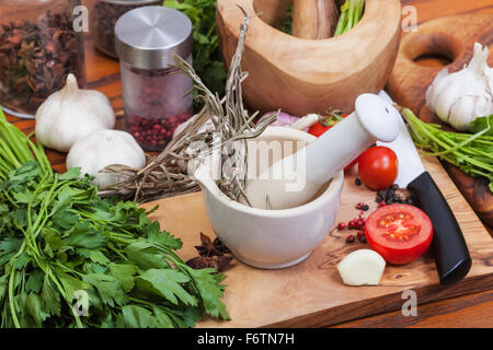Kochen Gewürze - Stößel Rasen in Keramik Mörser und Gewürzen auf Tisch Stockfoto