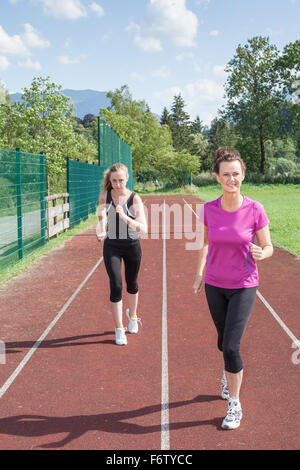 Zwei Frauen zusammen auf dem richtigen Weg laufen und Freundschaftsrennen - selbstbewusste Brünette Frau schlagen blonde Frau im Rennen Stockfoto