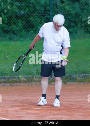 Senior woman Tennis spielen auf einem Kies-Gericht Stockfoto