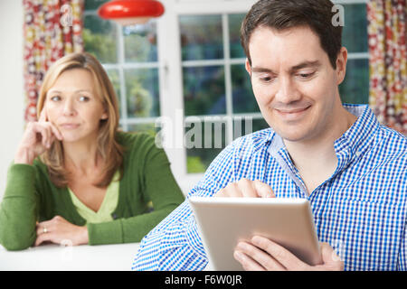 Unglückliche Frau am Tisch als Partner nutzt Digital-Tablette Stockfoto