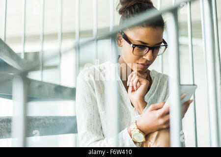 Junge Frau Aon Wendeltreppe auf Handy Stockfoto