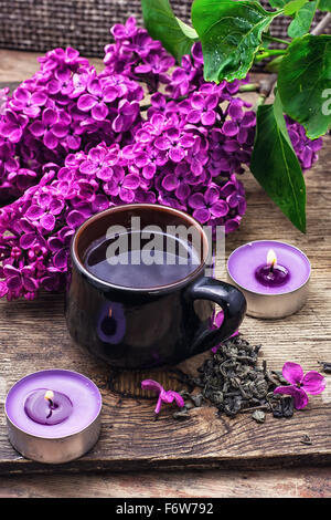 Gebrochene duftenden Zweig mit lila Blumen und brennenden Kerzen. Stockfoto