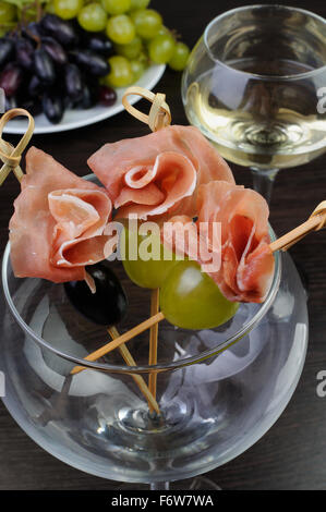 Vorspeise von Schinken mit Weintrauben am Spieß im Glas Stockfoto