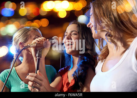 glückliche junge Frauen singen Karaoke im Nachtclub Stockfoto