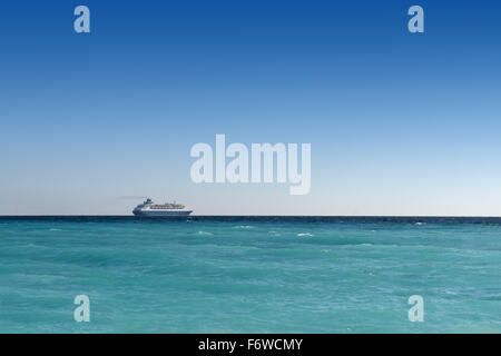 Kreuzfahrtschiff Segeln entfernt am türkisfarbenen Wasser und blauer Himmel Hintergrund Stockfoto
