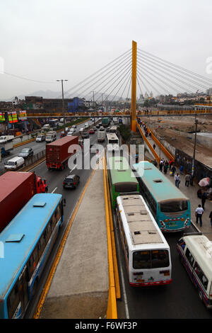 Busse und geschäftiger Verkehr auf der Autobahn Av Panamericana Norte neben dem Fluss Rimac und der Fußgängerbrücke Puente Rayito de Sol im Zentrum von Lima, Peru Stockfoto