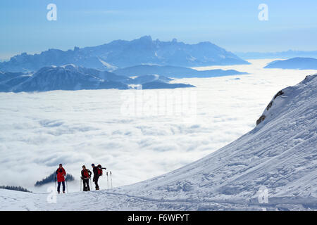 Drei Personen Rücken-Langlauf aufsteigenden, Hochkönig, Meer von Nebel im Tal der Salzach und Dachstein-Sortiment in der backgr Stockfoto