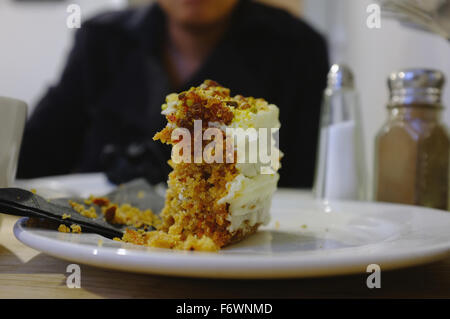 Ein halb gegessenen Stück Karottenkuchen auf einer Platte in einem Café in Brighton. Stockfoto