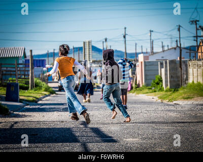 Kinder, die entlang einer Straße im Township Khayelitsha, Kapstadt, Western Cape, Südafrika Stockfoto
