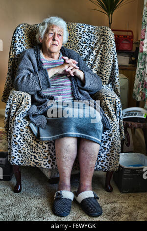 Eine alte Dame sitzt auf einem Stuhl Stockfoto