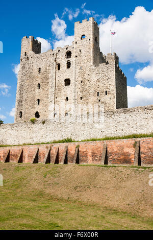 Rochester, Englisch mittelalterlichen Burg. Trockengraben mit späteren Mauer und dahinter, der äußeren Ringmauer. Hintergrund, massive halten gegen den blauen Himmel. Stockfoto