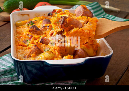 Auflauf mit Wurst, Speck und Äpfeln in einen Kürbis-Käse-sauce Stockfoto