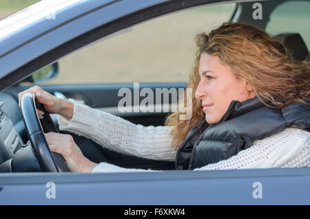 Frau ist ihr Auto zu fahren und schieben das Horn Stockfoto