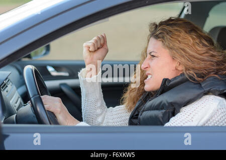 Frau Geste ist, fahren ihr Auto sehr aggressiv und gibt mit seiner Faust Stockfoto