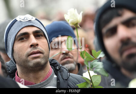 Hanau, Deutschland. 21. November 2015. Ein Mann trägt eine Mütze mit einem Peace-Zeichen, der eine weiße rose trägt, besucht eine Gedenk-Kundgebung für die Opfer der Terroranschläge Paris, auf dem Freiheitsplatz in Hanau, Deutschland, 21. November 2015. Foto: ARNE DEDERT/Dpa/Alamy Live-Nachrichten Stockfoto