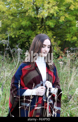 schöne junge Frau, die zu Fuß durch ein Feld lange Gras im Herbst Stockfoto