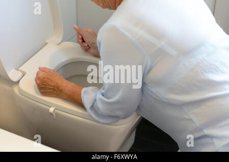 Frau, die immer krank und Erbrechen über ein WC Schüssel kniete mit ihren Armen ruht auf dem Sitz, Nahaufnahme ihres Körpers Stockfoto