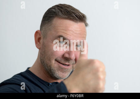 Blauäugige Mann mittleren Alters mit einer positiven Einstellung lächelt und zeigt Daumen oben, Portrait mit textfreiraum auf grau Stockfoto