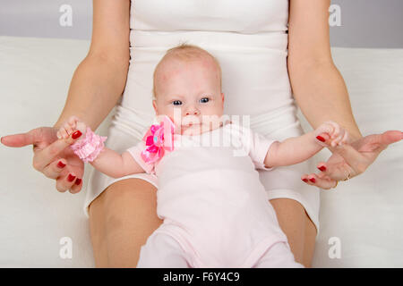 ein zwei-Monats-Baby auf dem Rücken auf der Mutter Schoß liegend und mit Blick auf Ihr Stockfoto