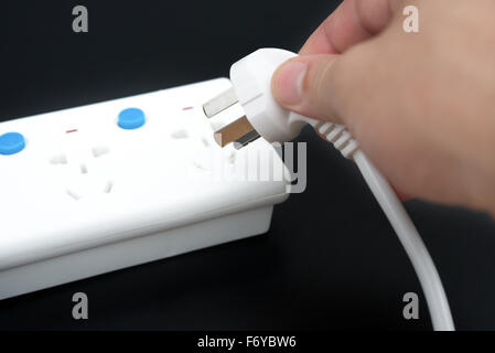 setzen einen Stecker an einem Multi Steckdosen Erweiterung auf schwarz Stockfoto