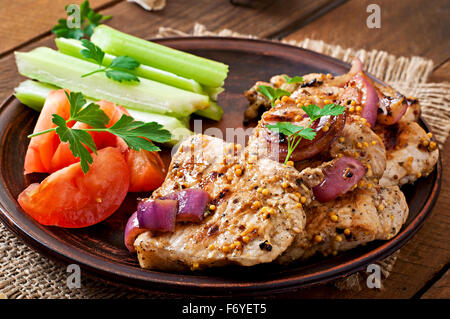 In Scheiben geschnitten Schweinefleisch gegrillt mit Gemüse auf braune Keramikplatte. Stockfoto