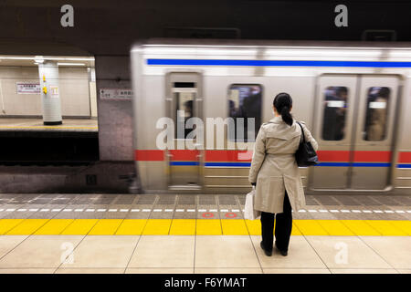 Eine japanische Frau wartet im Untergrund für einen vorbeifahrenden Zug Stockfoto