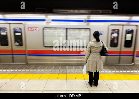 Eine japanische Frau wartet im Untergrund für einen vorbeifahrenden Zug Stockfoto