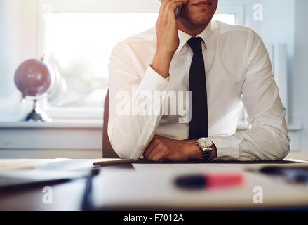Nahaufnahme eines Business-Mann sitzt an seinem Schreibtisch am Telefon sprechen