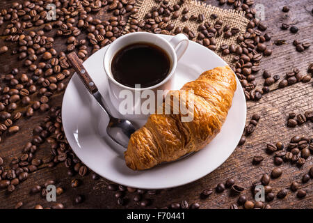 Kaffee und ein Croissant auf hölzernen Hintergrund Stockfoto