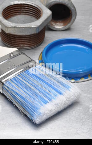 Blauer Farbe Deckel mit Pinsel und Metall Sanitär-Teile auf grauem Hintergrund Metall Stockfoto