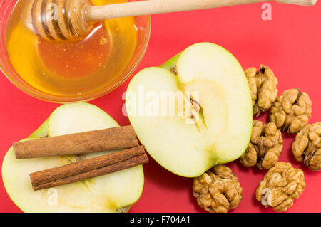 Frische Walnüsse, natürlichem Honig, Zimt und Äpfeln auf rotem Grund. Gesundes dessert Stockfoto