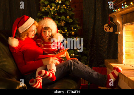 Weihnachten Geschichtezeit mit Mutter und Kind vor Kamin im x-mas tree Stockfoto