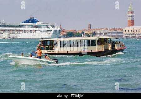 Riesige Kreuzfahrtschiff über die venezianische Lagune mit Vaporetto Wasserbus im Vordergrund Venedig Veneto Italien Europa Stockfoto