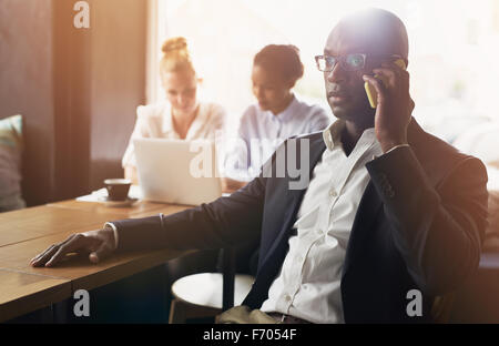 Schwarzer Geschäftsmann mit Mobiltelefon, Weiß und Schwarz Business Woman im Hintergrund Stockfoto