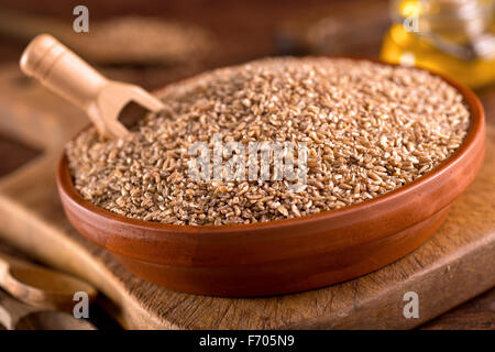 Eine Schüssel mit rohen Bulgar Weizen auf einem rustikalen Hintergrund. Stockfoto