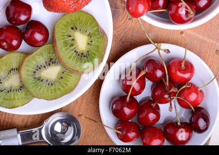 Obst mit Kirsche, Erdbeere, Kiwi auf Holzplatte Stockfoto