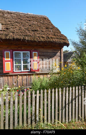 Das Museum der Landschaft Masowien in Sierpc, Polen. Alte hölzerne Bauer reetgedeckten Bauernhaus mit dekorativen Fensterläden. Stockfoto