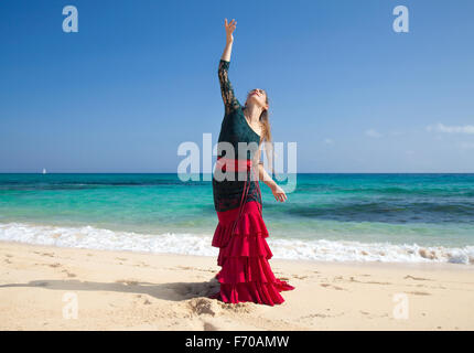 junge attraktive Frau im roten und grünen Flamenco Kleid von Ocean shore Stockfoto