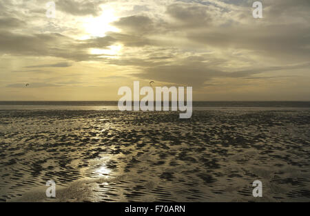 Blick über weite nassen Strandsand in Richtung Mann Windsurfen unter grauen Wolken Sonnenuntergang Himmel, St. Annes, Fylde Küste, Lancashire Stockfoto