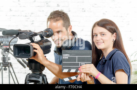 ein Lächeln auf den Lippen Kameramann und hübsche junge Frau mit einer Filmkamera und Klöppel Stockfoto