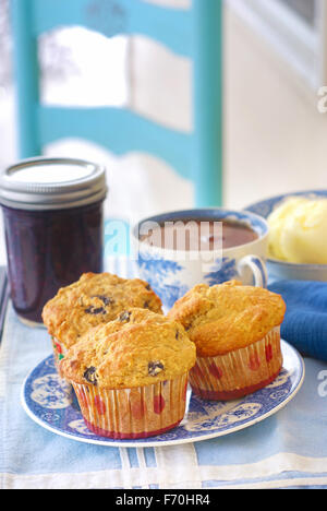 Vintage Teller mit Vollkorn (Weizen/Hafer/Mandel)-Blaubeer-Muffins mit Blaubeeren Marmelade, frische Butter und Tasse heißen schwarzen Tee Stockfoto