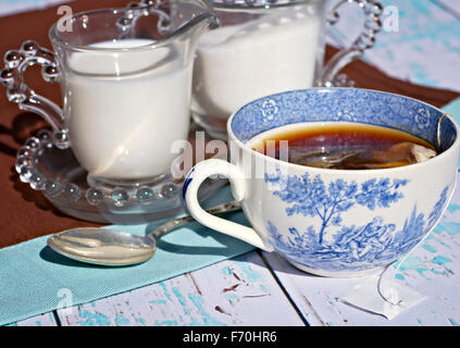 Tee in einem antiken Teetasse mit Milch und Sahne auf rustikalen Tisch Stockfoto