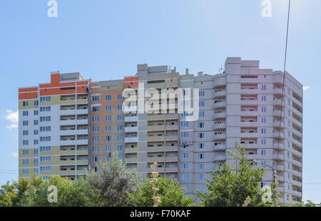 Industriekletterer in äußere Verkleidung an den Bau von einem mehrstöckigen Wohnhaus beschäftigt. Stockfoto