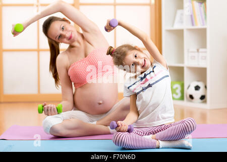 Schwangere Mutter und Tochter Kind Übung nach Hause Stockfoto