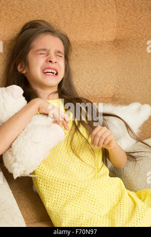 kleines Mädchen weinend auf einem Stuhl. Stockfoto
