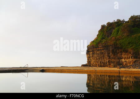 Landzunge Bluff erhebt sich über den Wombarra-Felsen-Pool - ein Meerwasser Pool entlang der Küste. Stockfoto