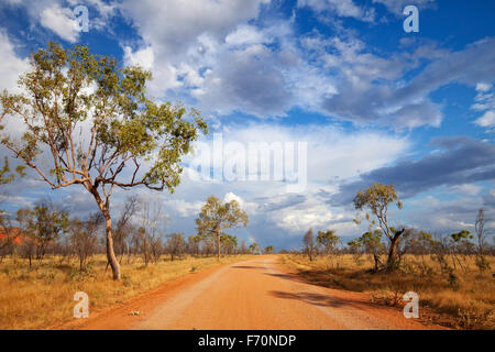 Eine unbefestigte Straße durch das australische Outback mit einem Regenbogen am Ende der Straße. Fotografiert in den Purnululu National Pa Stockfoto