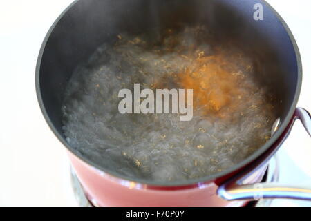 Von oben betrachtet ein Ei in einem roten Topf auf einem Herd kochen. Stockfoto