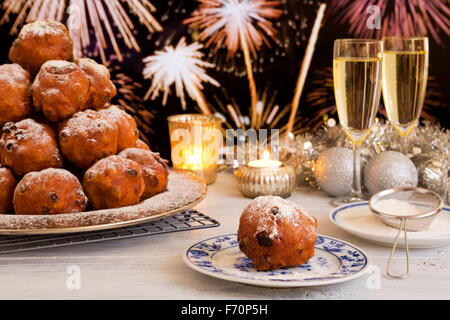 "Oliebollen", traditionelle holländische Blätterteig für Silvester. Mit Champagner und Feuerwerk im Hintergrund. Stockfoto