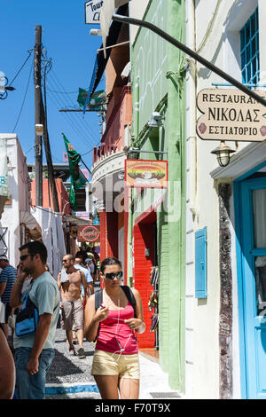 Santorini. Touristen zu Fuß durch die typischen engen gepflasterten Straße mit Geschäften auf beiden Seiten, im alten Stadtzentrum von Fira im heißen Sommer. Stockfoto